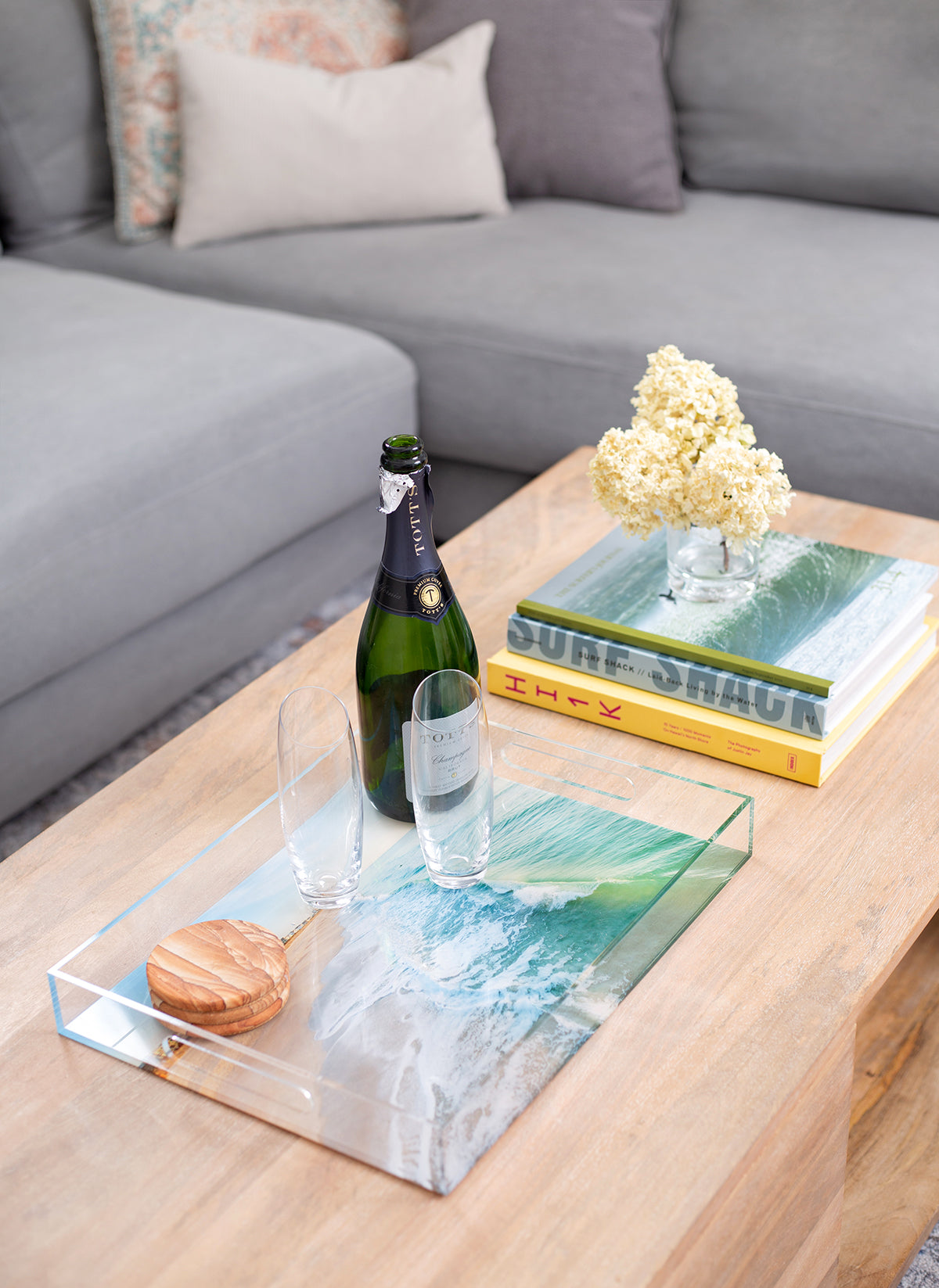 modern coastal coffee table decor with ocean photograph on clear acrylic serving tray